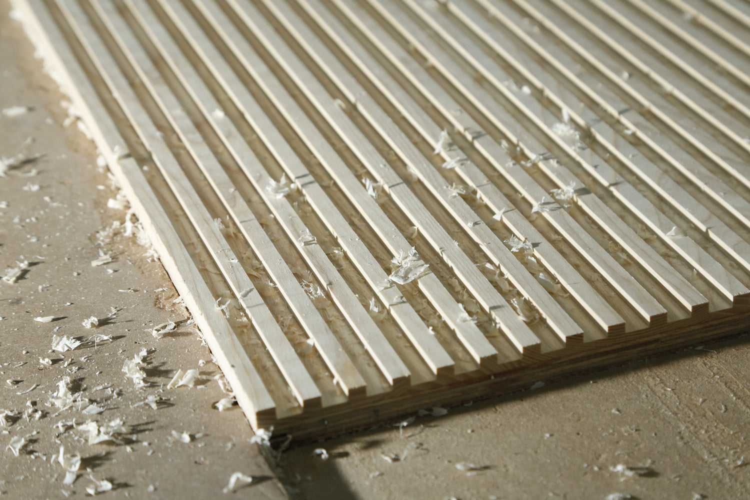 Close up of Ash wood fluted wall panel with wood shavings, as if to imply freshly fluted. By Element